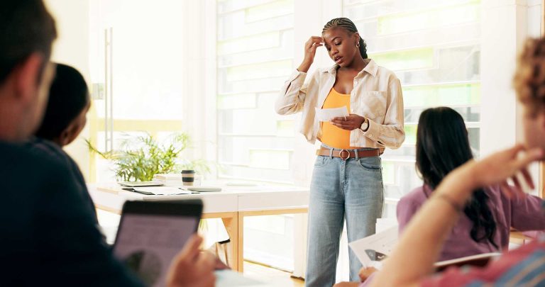 Femme présentant devant un groupe dans une salle lumineuse.