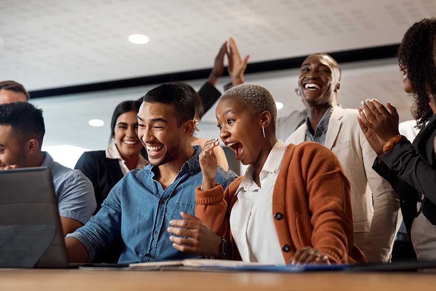 Groupe de collègues célébrant devant un ordinateur.